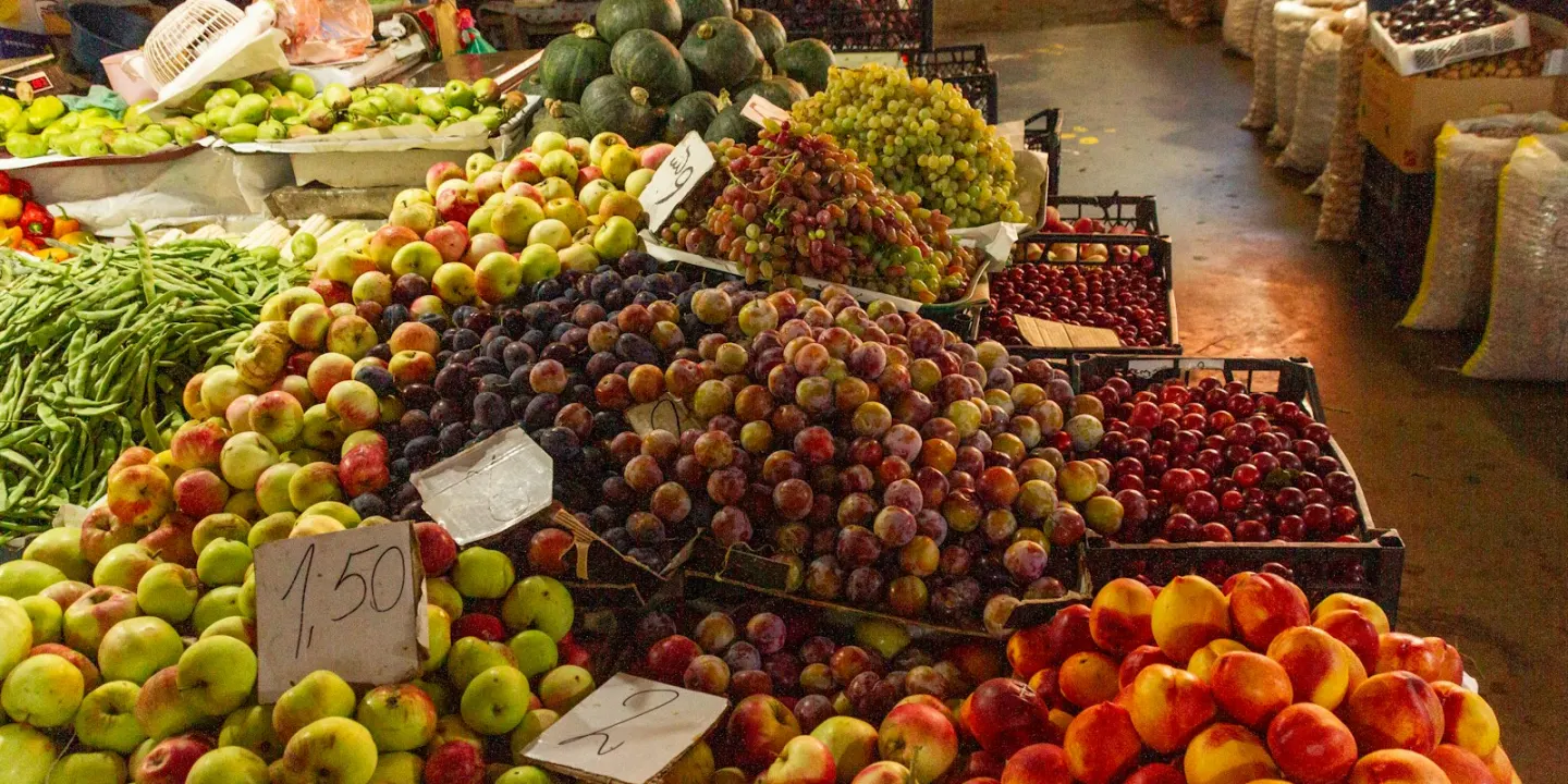 Tarabă în piață cu struguri, prune, dovleci și legume de toamnă